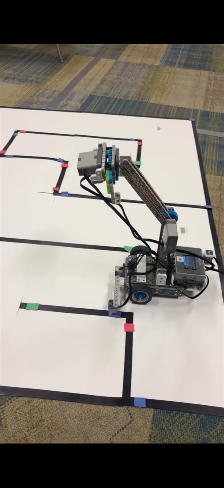 Autonomous VEX robot with its claw arm on the taped maze grid